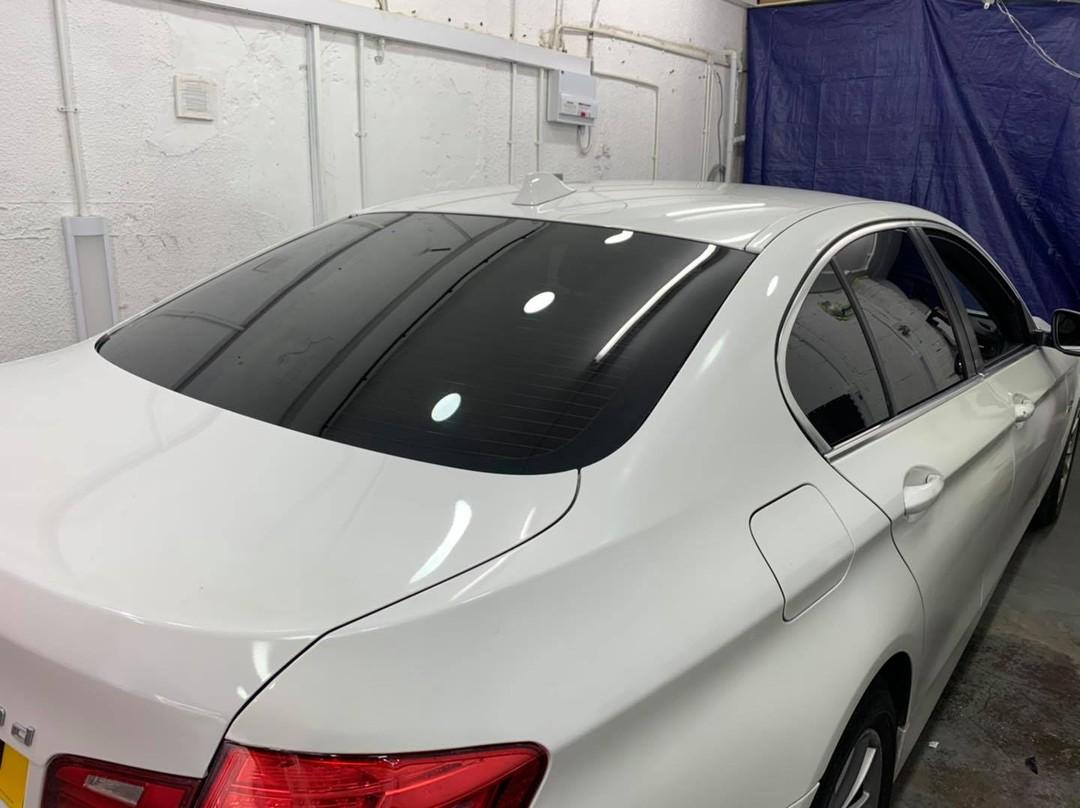 White BMW saloon with dark tinted rear windows inside the workshop