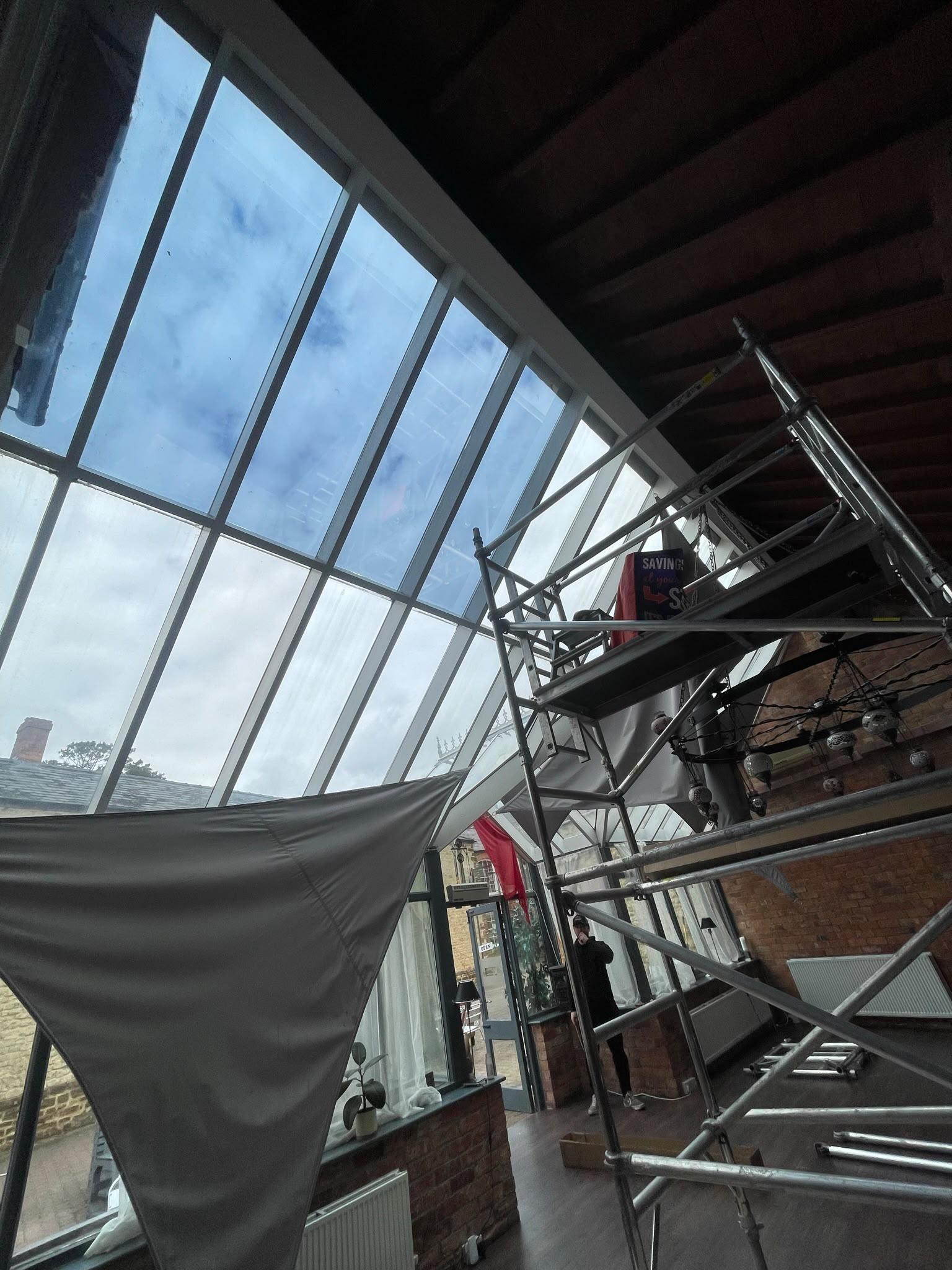 Scaffold tower under a glass conservatory roof during a roof film fit