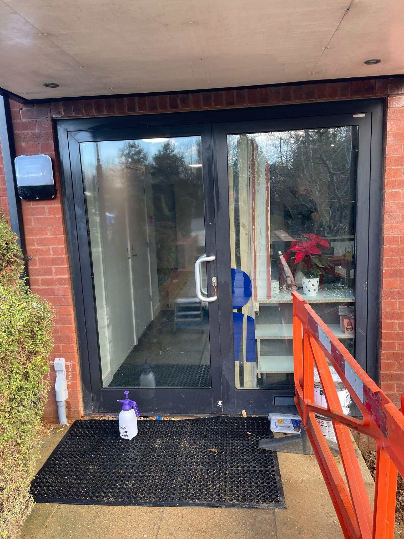Communal entrance doors with clear glass, the hallway inside visible