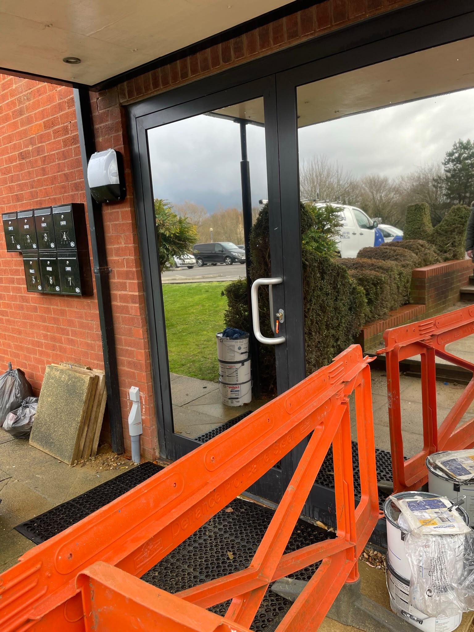 Communal entrance doors after reflective film: the glass shows the trees and car park, not the hallway