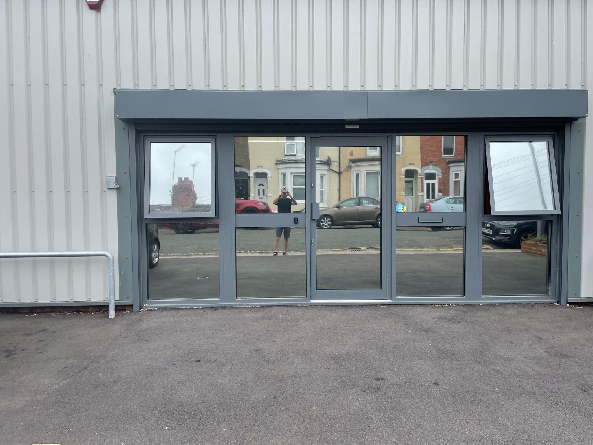 The same office front after reflective window film: the glass reflects the street and the office is hidden