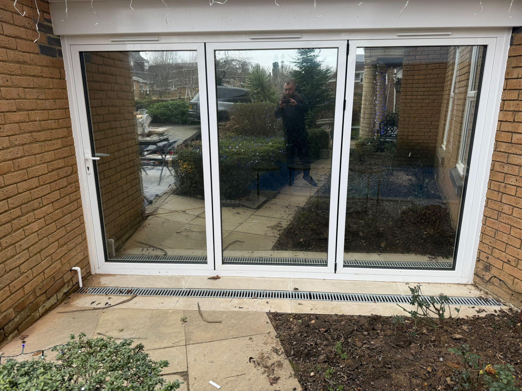 White bifold doors with reflective film showing the patio and garden