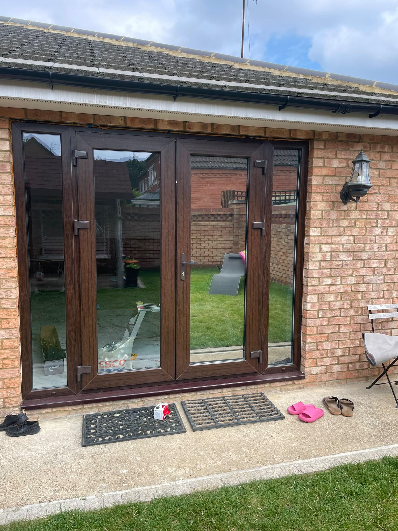 Brown uPVC French doors on a brick extension with clear glass