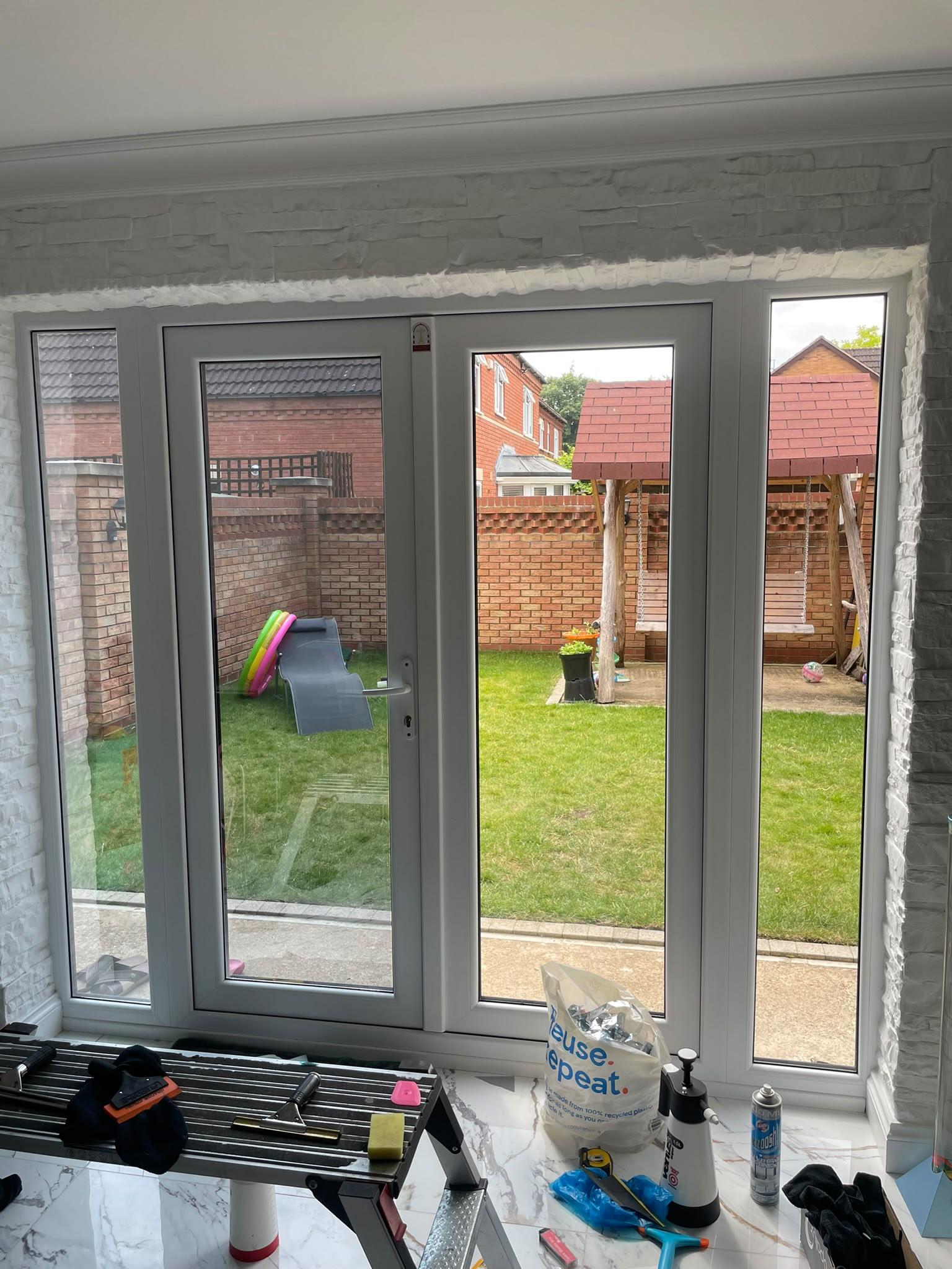View out through filmed French doors from inside, with fitting tools on the floor